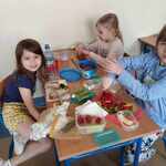 Trzy dziewczynki przy stoliku wykonują zdrowe kanapki z przygotowanych składników.jpg
