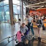 Trzy uczennice uczą się jeździć na wózku inwalidzkim w Centrum Nauki Kopernik.jpg