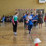Dziewczynka w niebieskiej koszulce bierze udział w konkurencji sportowej.