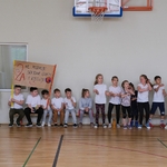 Grupa uśmiechniętych dzieci trzyma transparent dopingujący swoją drużynę.