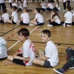 Grupa dzieci czeka w rzędach na start konkurencji.