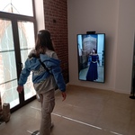 Uczennica przygląda się swojej podobiźnie w stroju damy dworu wyświetlanej na ekranie multimedialnym.