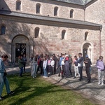 Grupa uczniów stoi pod murami starej kolegiaty w Kruszwicy.