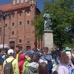 Uczniowie stoją pod pomnikiem Mikołaja Kopernika.
