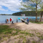 Grupa uczniów spaceruje brzegiem jeziora.