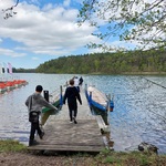 Dwóch uczniów spaceruje po molo nad jeziorem. Przy molo zacumowana jest łódka. 