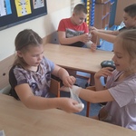 Czworo uczniów ćwiczy opatrywanie ręki za pomocą bandaża.