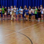 Duża grupa dziewczyn odbiera nagrody za rywalizację sportową z rąk Dyrektora szkoły i nauczycielek.