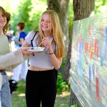 Uśmiechnięte uczennice wykonują za pomocą farb rysunki na folii spożywczej.