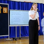 Dziewczynka z klasy ósmej śpiewa piosenkę w duecie ze swoim młodszym bratem.