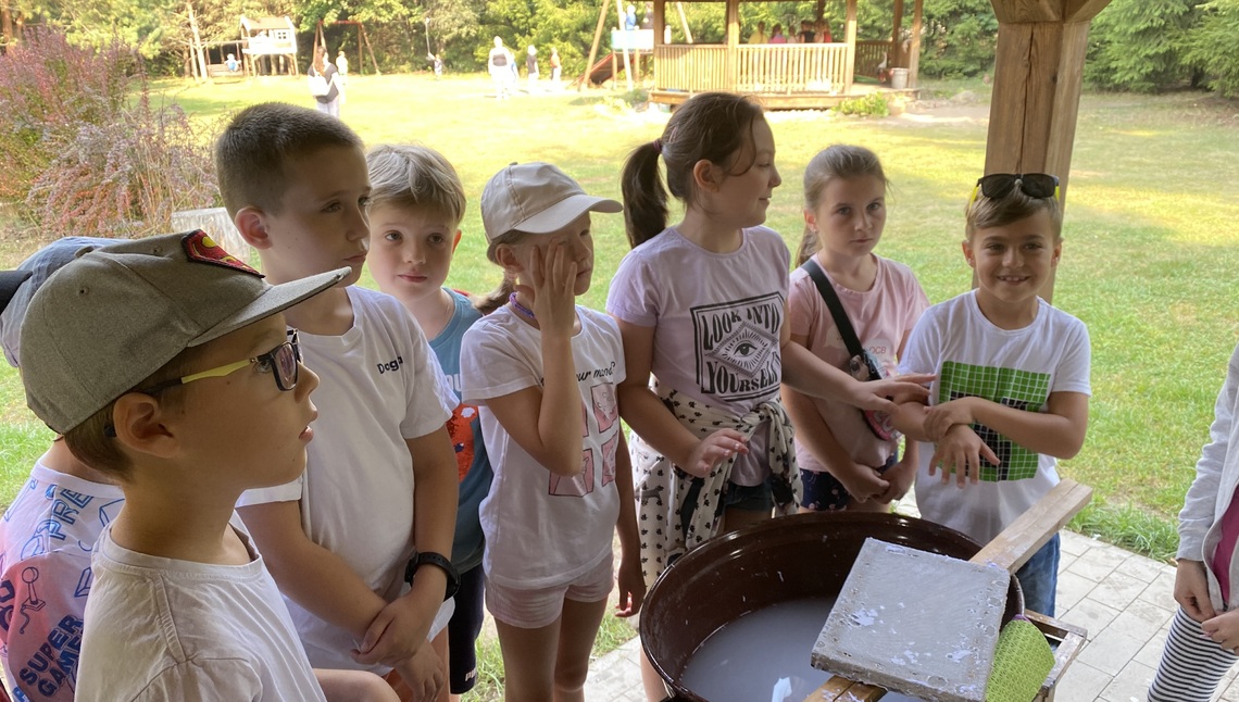 Grupa dzieci przygląda się w jaki sposób robi się papier czerpany.jpg