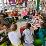 W bibliotece uczniowie klasy 5a siedzą na pufach w kręgu. Słuchają głośnego czytania książki..jpg