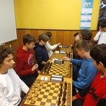 Zawodnicy SP 26 i SSP3 siedzą naprzeciwko siebie przy szachownicach.jpg