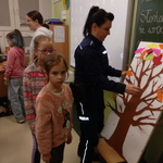 Dwie dziewczynki i policjantka przypinająca kolorowy listek do makiety..jpg