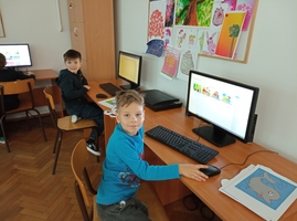 Dwoje uczniów prezentuje wykonane przez siebie prace na komputerze.jpg