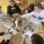 Dzieci siedzą przy stoliku i dekoruję choinki z papieru.jpg