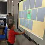 Uczeń odkrywa karty memory na tablicy interaktywnej.jpg