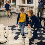 Dwóch chłopców gra w wielkie szachy na podłodze korytarza..jpg