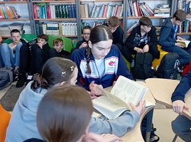 Uczniowie w biobliotece pracują w grupach_ przeglądając książki.jpg