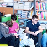 Chłopcy_ siedząc na pufach w bibliotece szkolenj_ przeglądają książkę.jpg