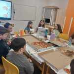 uczniowie przy stole jedza pizze.jpg