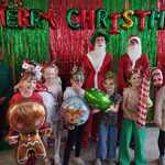 Uczniowie pozują do zdjęcia z bożonarodzeniowymi rekwizytami na tle świątecznej fotobudki.jpg