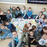 grupa dzieci siedzi przy plakacie z okazji Dnia Praw Dziecka.jpg