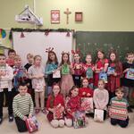 Świątecznie ubrani uczniowie pozują do zdjęcia z upominkami bożonarodzeniowymi..jpg
