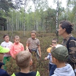 Uczniowie w trakcie wycieczki przyrodniczej uważnie słuchają przewodnika.