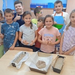 Dzieci prezentują przygotowany przez siebie chleb.