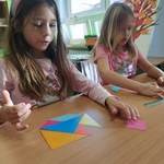 dwie dziewczynki ukladaja na lawce tangram.jpg